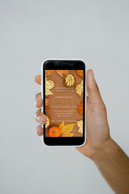 Hand holding a smartphone displaying the Beige Gold Leaves Pumpkin Thanksgiving Evite, customizable via Canva for electronic invitations.