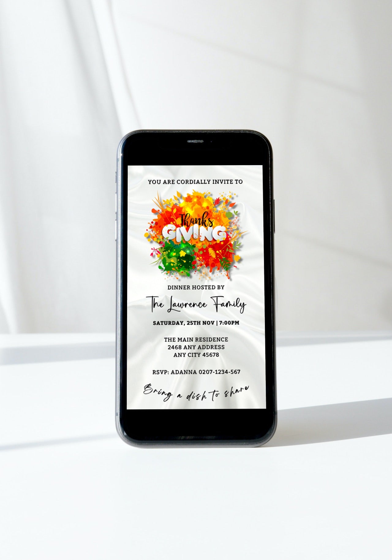 Cell phone displaying a personalized Thanksgiving Dinner Evite template with a colorful design and white silk background.