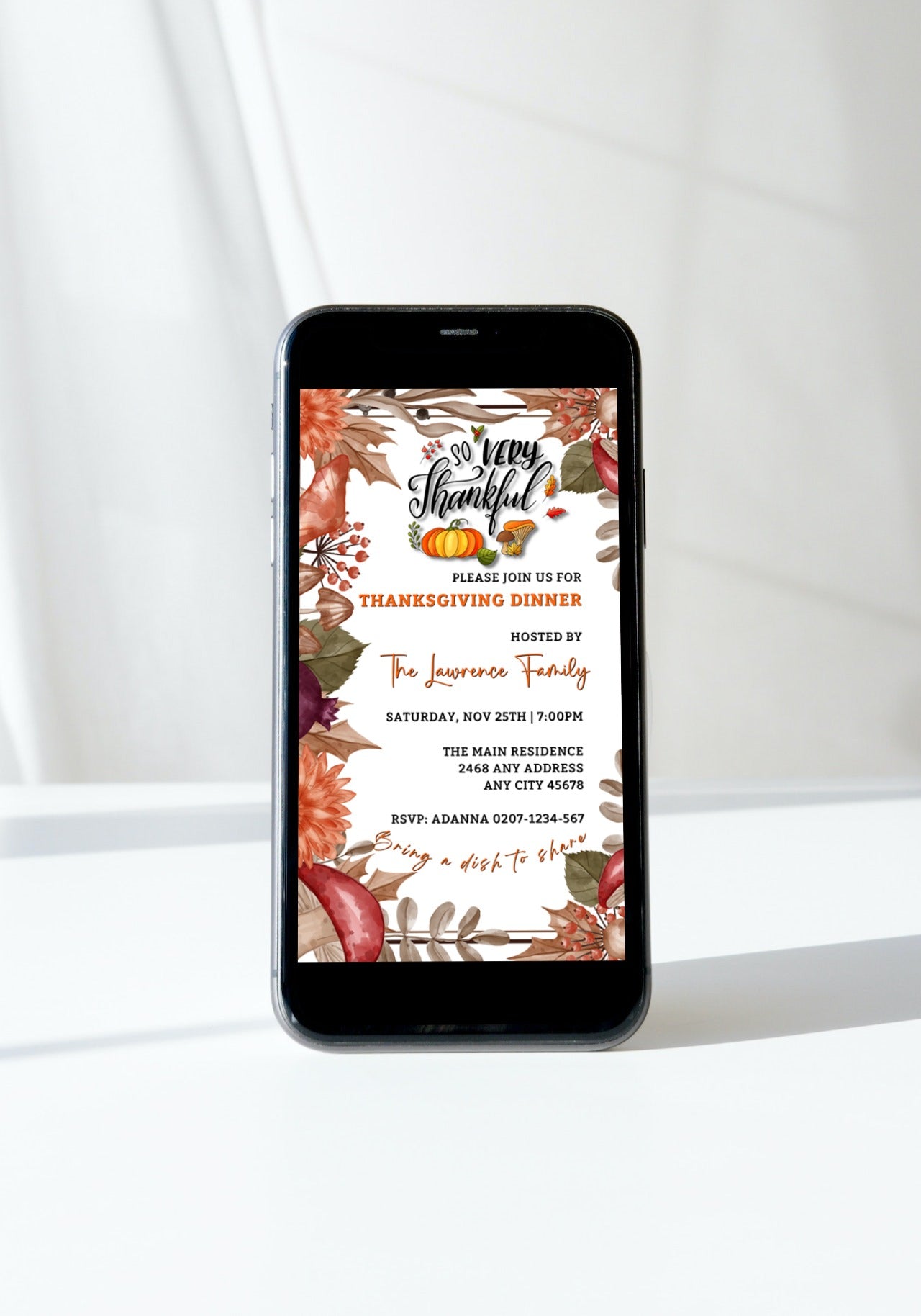 Smartphone displaying an editable digital invitation for a Thanksgiving dinner, featuring an autumn leaves theme from URCordiallyInvited.