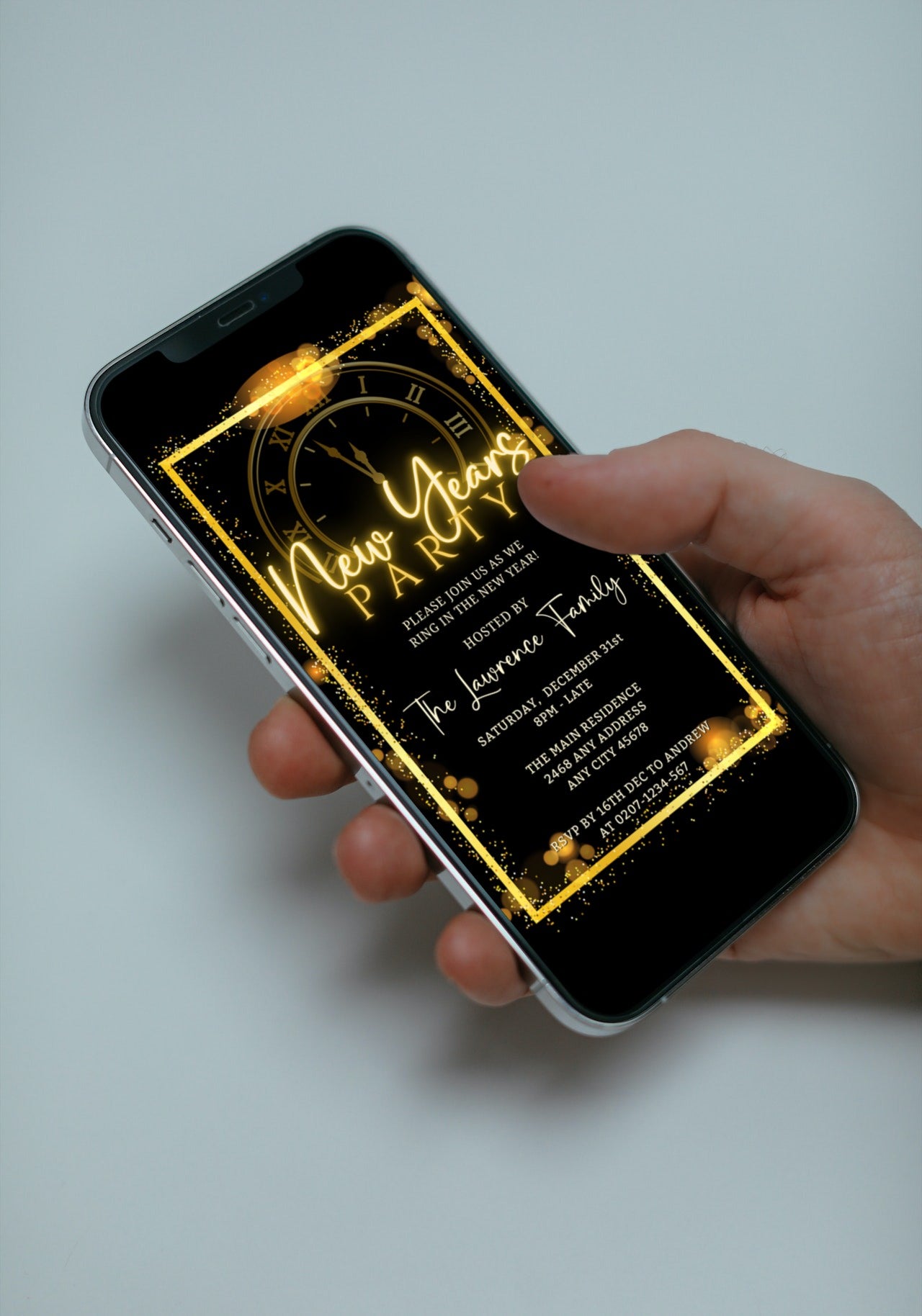 Hand holding a smartphone displaying the Editable Digital Roman Clock Golden Frame New Years Party Evite template from URCordiallyInvited.