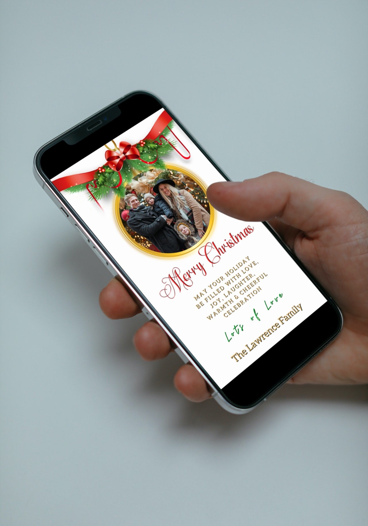 Hand holding a smartphone displaying an editable digital white oval bold red Merry Christmas ecard with a photo frame.