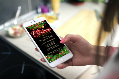 Hand holding a smartphone displaying an editable Green Red Neon Ornaments Christmas Party Evite from URCordiallyInvited, customizable via Canva for easy digital sharing.