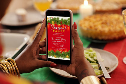 Person holding a phone displaying a Red Green White Ornaments Lights Christmas Party Evite template, ready for customization and electronic sharing.