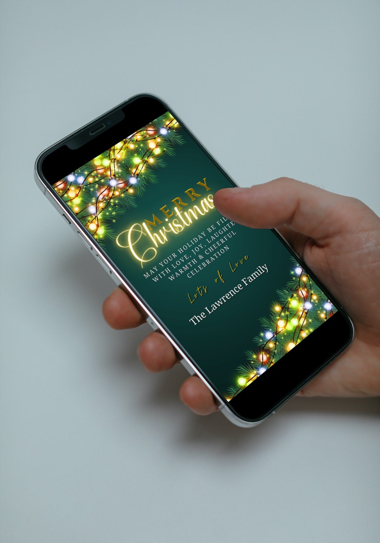Hand holding a smartphone displaying a Colourful Lights Neon Gold Green Merry Christmas Ecard template from URCordiallyInvited.