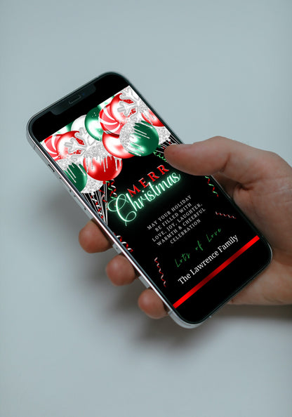 Hand holding a smartphone displaying a Red Neon Green Balloons Merry Christmas Ecard, customizable via Canva for digital invitations.