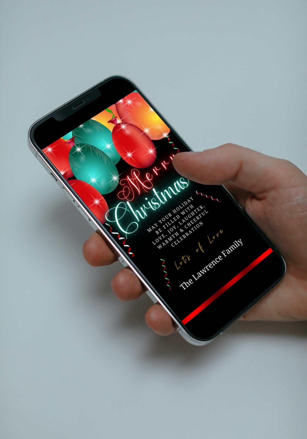 Hand holding a smartphone displaying the Neon Red Teal Balloons Sparkle Merry Christmas Greeting Ecard, highlighting its customizable and digital features.