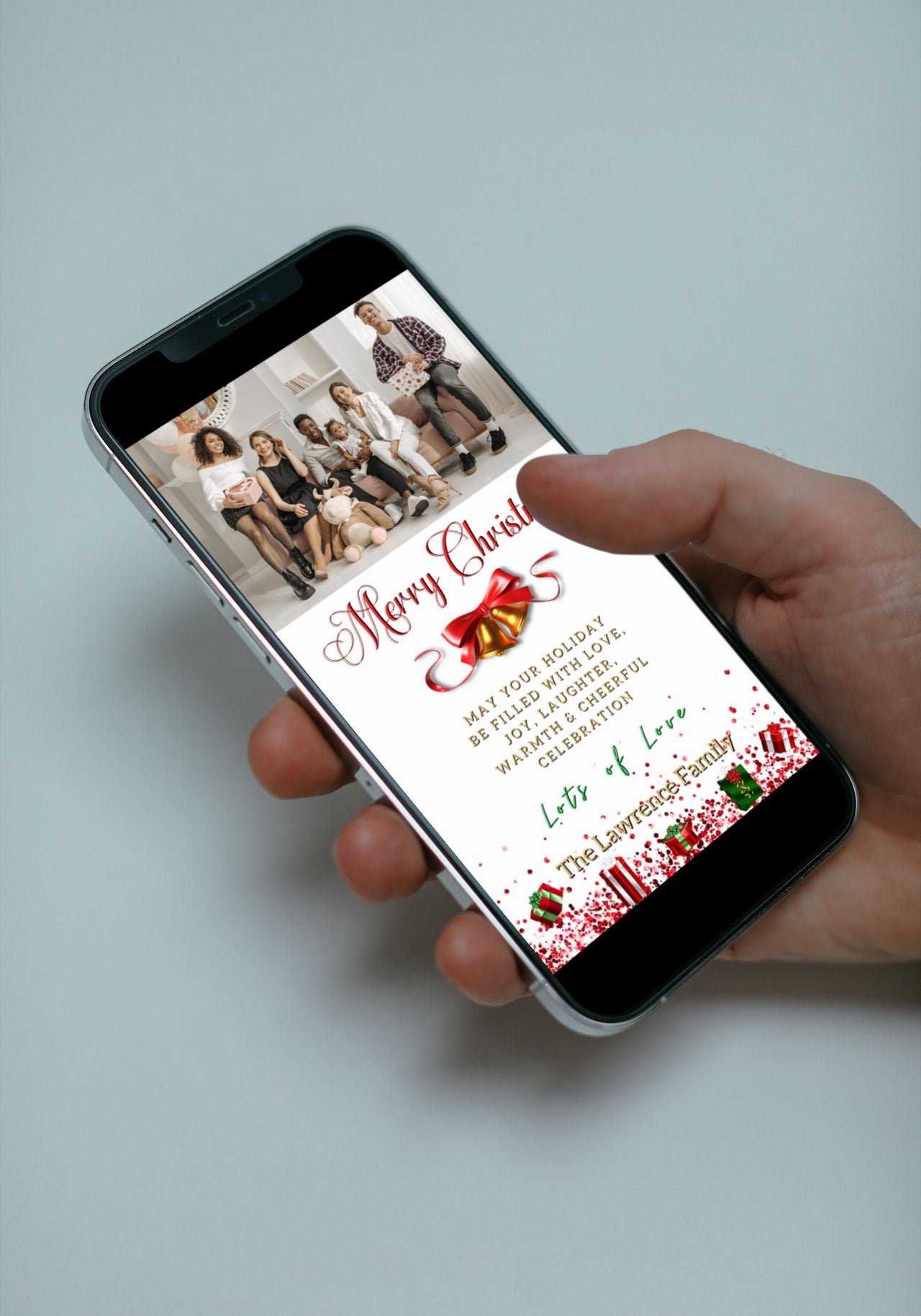 Hand holding a smartphone displaying the Gold Red Bell Confetti Glitter Merry Christmas Greeting Ecard template from URCordiallyInvited.