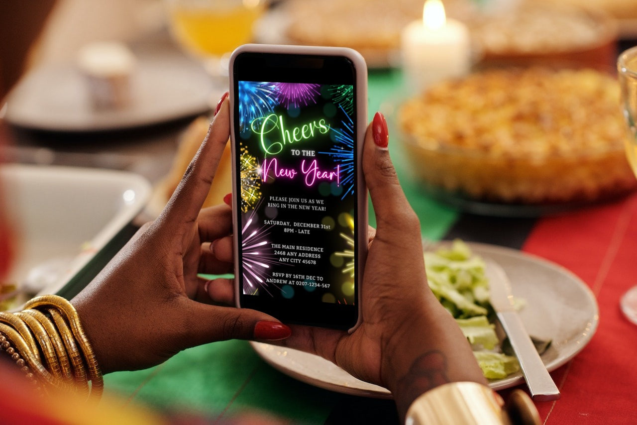 Person holding a phone displaying a digital Neon Pink Green Fireworks New Year's Eve Party Evite template for customization.