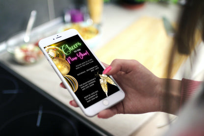Hand holding a smartphone displaying Neon Pink Green Ornaments Cheers | New Years Eve Party Evite, a customizable digital invitation template from URCordiallyInvited.