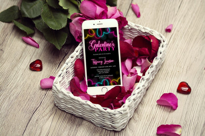 Cell phone in a basket of rose petals showcasing the Pink Neon Colourful Boarder | Galantines Party Evite for editable digital invitations.