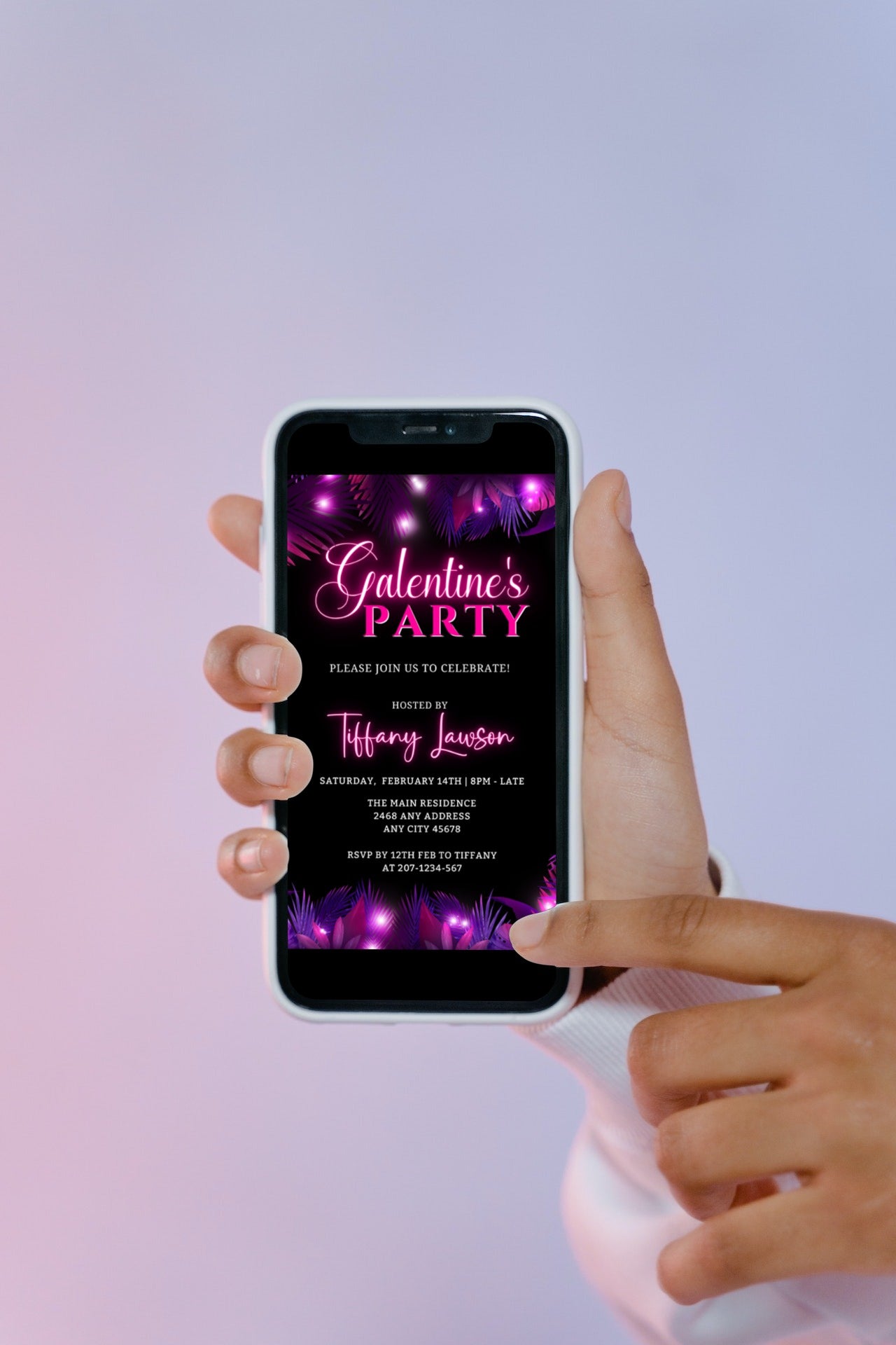 A hand holding a smartphone displaying a customizable Purple Pink Neon Palm Leaves Galentines Party Evite template.