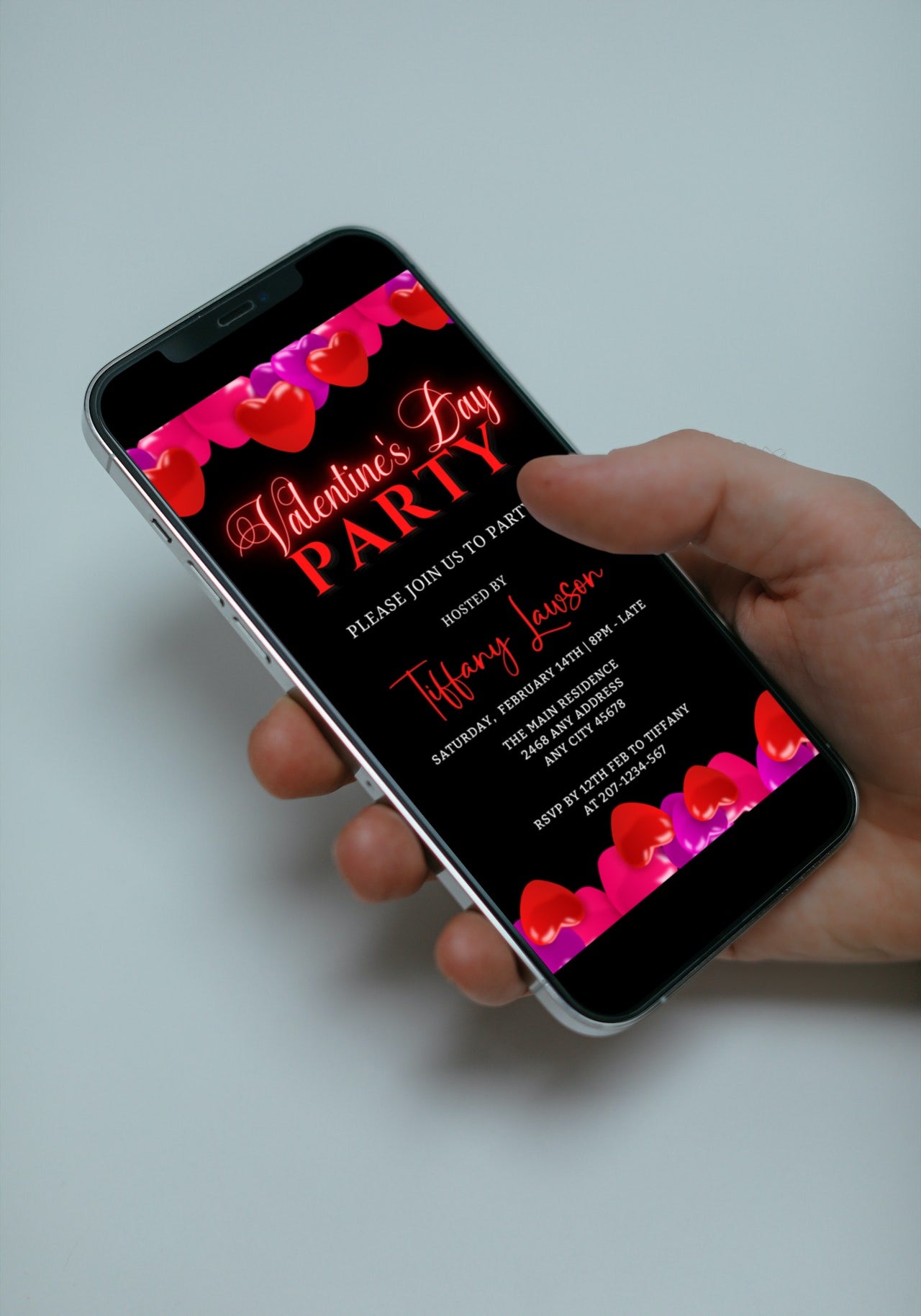Hand holding a smartphone displaying the Black Pink Red Hearts Valentine's Party Evite, a customizable digital invitation template available on URCordiallyInvited.