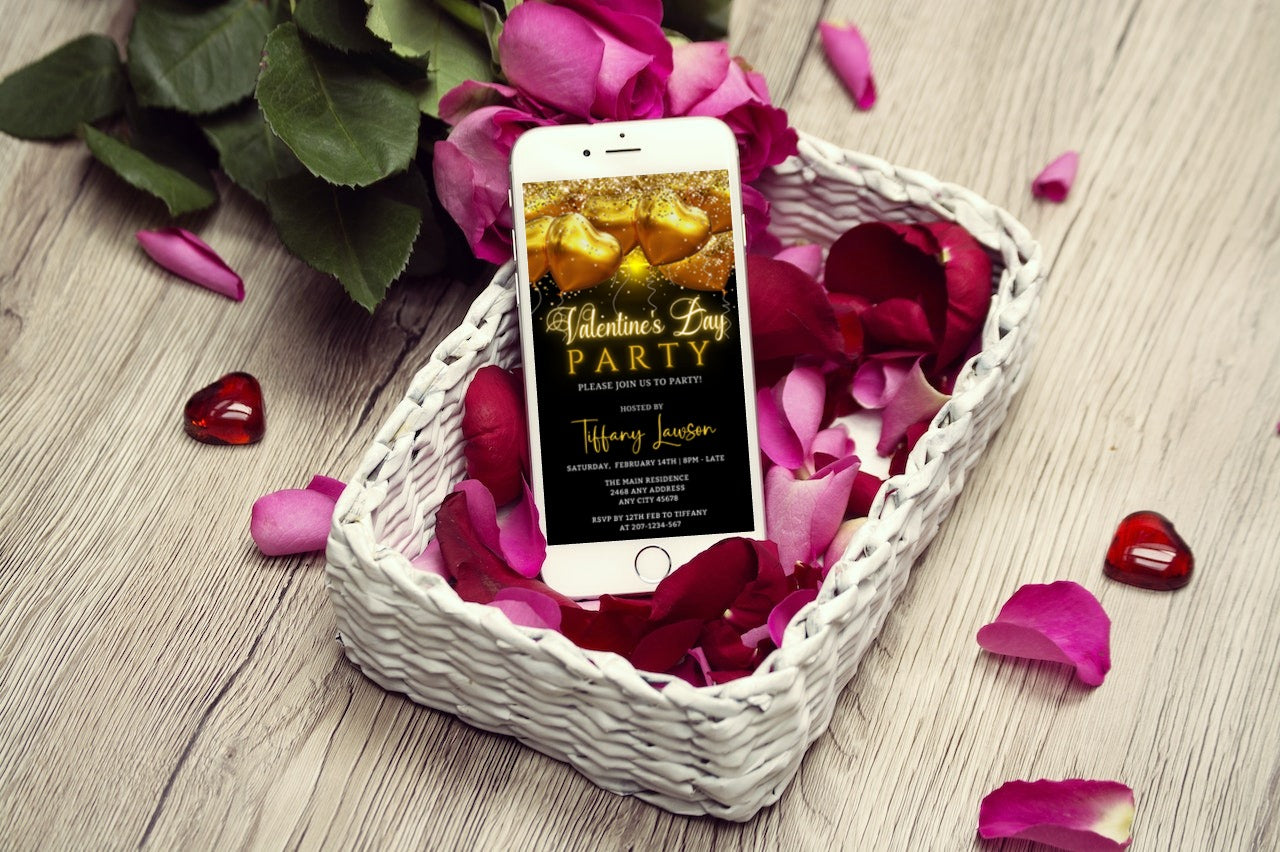 Cell phone displayed in a basket of rose petals, showcasing the Neon Golden Heart Balloons | Valentines Party Evite.