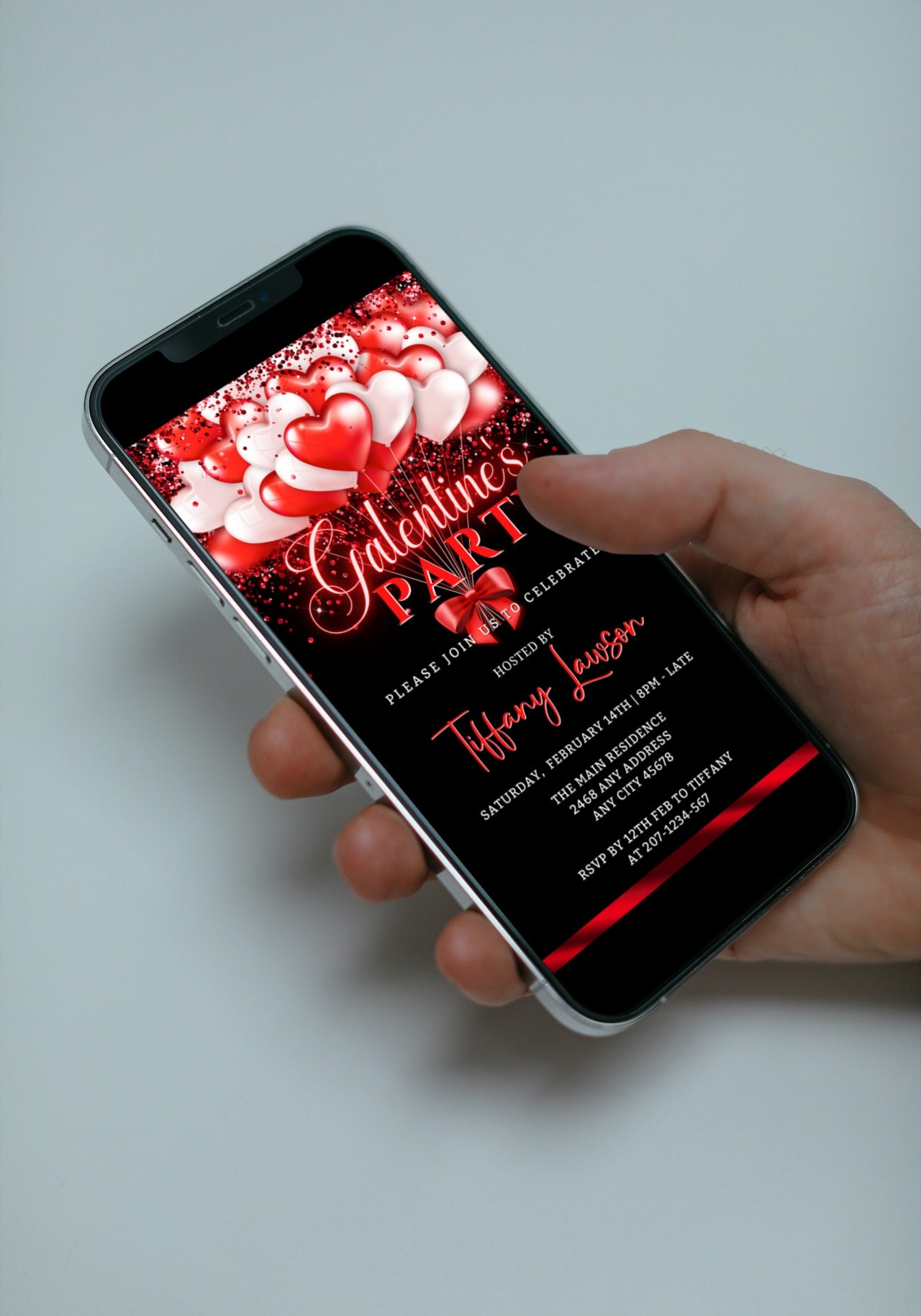 Hand holding a smartphone displaying a Neon Red White Hearty Balloons Galentines Party Evite template for customization and digital sharing.