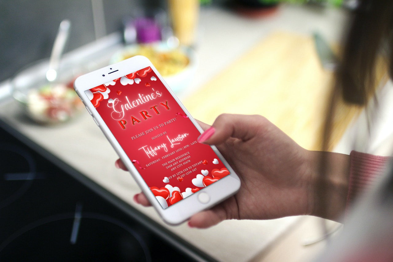 Hand holding a phone displaying a Red White Border Hearts | Galentines Party Evite template, customizable via the Canva app for digital invitations.