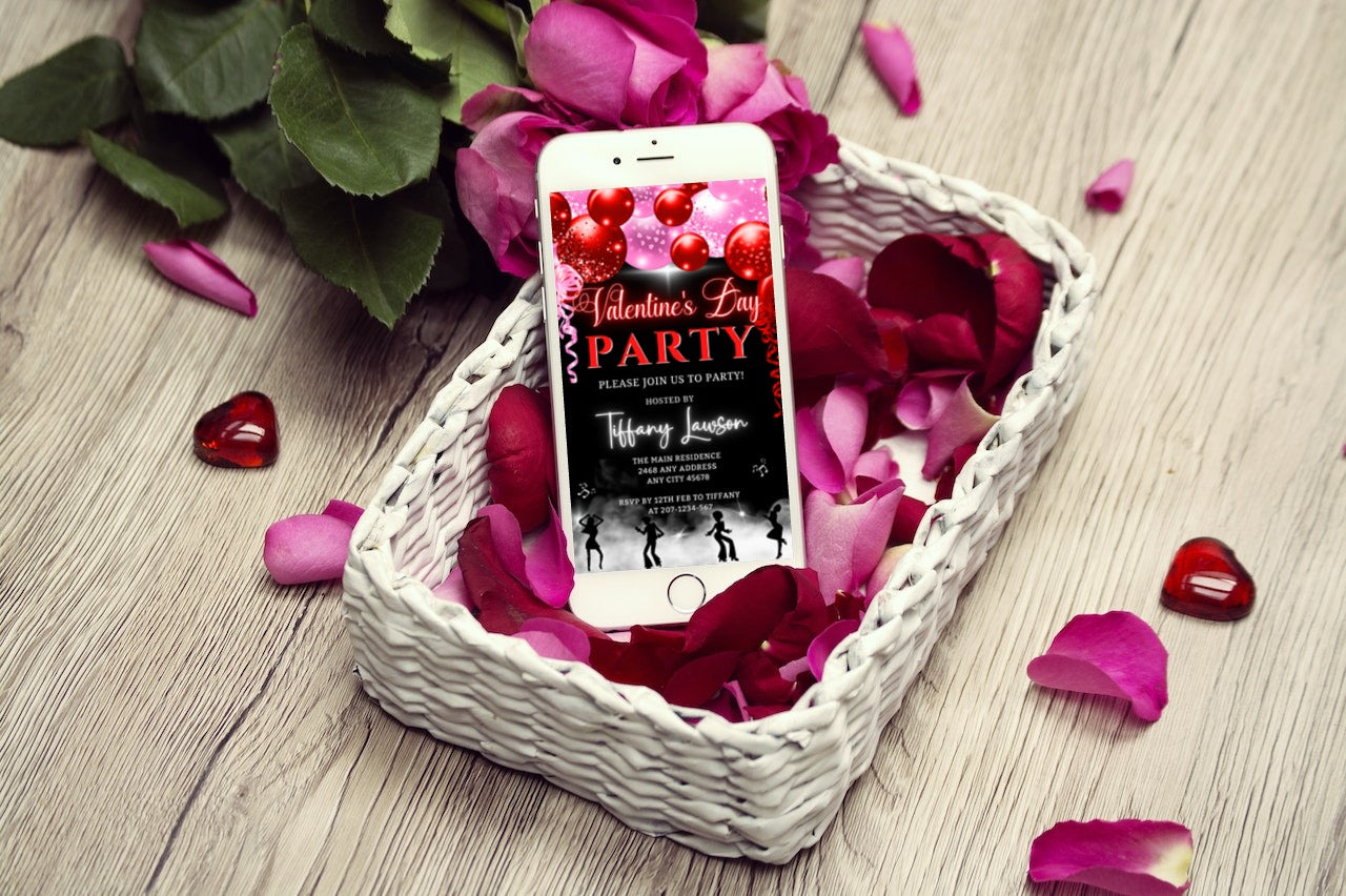 Cellphone in a basket of rose petals displaying Neon Red Pink Smoking Dancers Valentines Party Evite on screen.