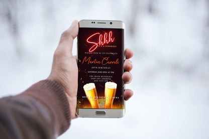 Hand holding a smartphone displaying a Red Neon Beer Mugs Surprise Birthday Party Evite, customizable via Canva for digital invitations.