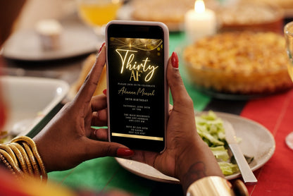 Person holding a smartphone displaying the customizable Black Gold Neon Sparkle | 30AF Birthday Evite from URCordiallyInvited.