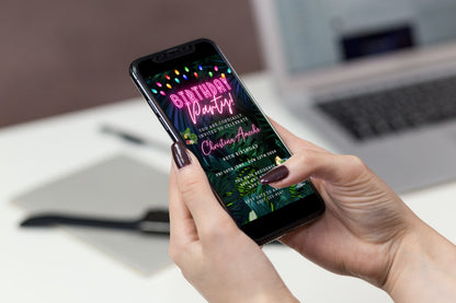 A hand holding a phone displaying a customizable digital Neon Pink Tropical Birthday Party Evite.