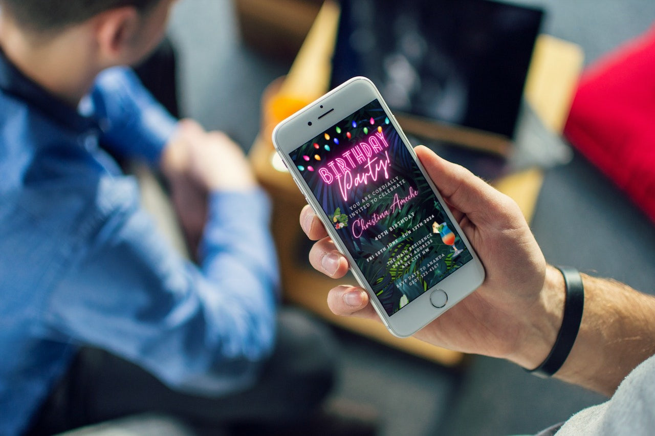 Person holding a smartphone displaying a customizable digital neon pink tropical birthday party evite from URCordiallyInvited.
