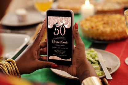 Person holding a smartphone displaying a customisable Rose Gold Balloons Glitter 50th Birthday Evite template from URCordiallyInvited.