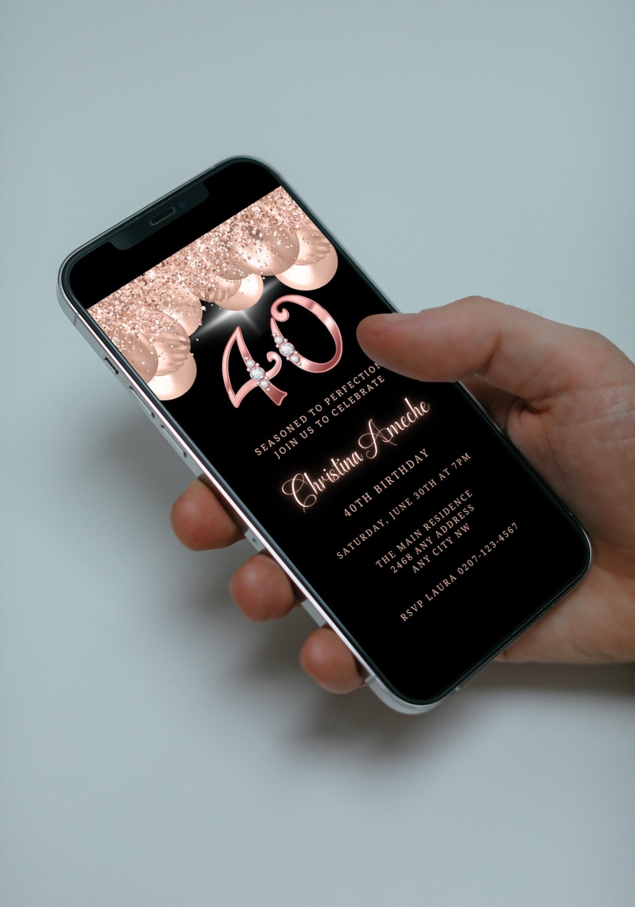 Hand holding a smartphone displaying a customizable 40th Birthday Evite with rose gold balloons and diamond studs from URCordiallyInvited.