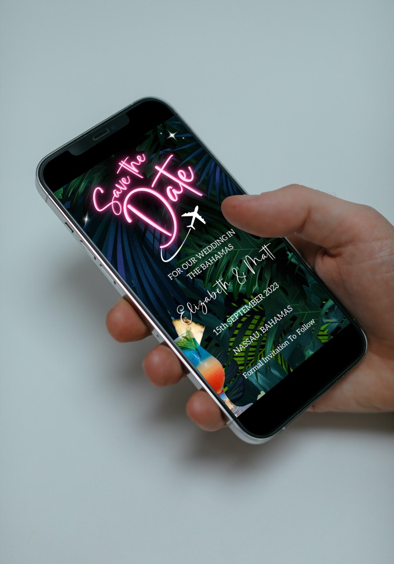 Hand holding a smartphone displaying the Editable Digital Neon Pink Destination | Save The Date Evite template, ideal for personalizing event details via Canva.