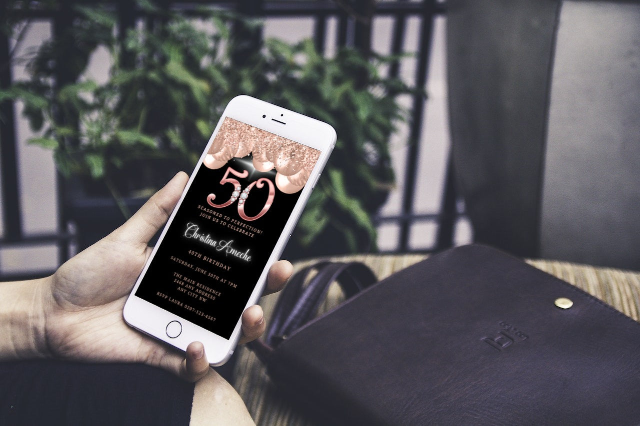 A hand holding a smartphone displaying a customisable Digital Rose Gold Balloons Diamond Studs | 50th Birthday Evite.