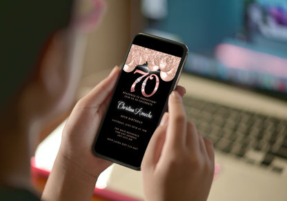 Person holding a smartphone displaying a customizable digital invitation for a 70th birthday with Rose Gold Balloons and Diamond Studs.