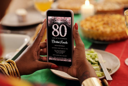 Person holding a phone displaying a customizable Rose Gold Diamond Glitter 80th Birthday Evite from URCordiallyInvited, ready for personalization via Canva.