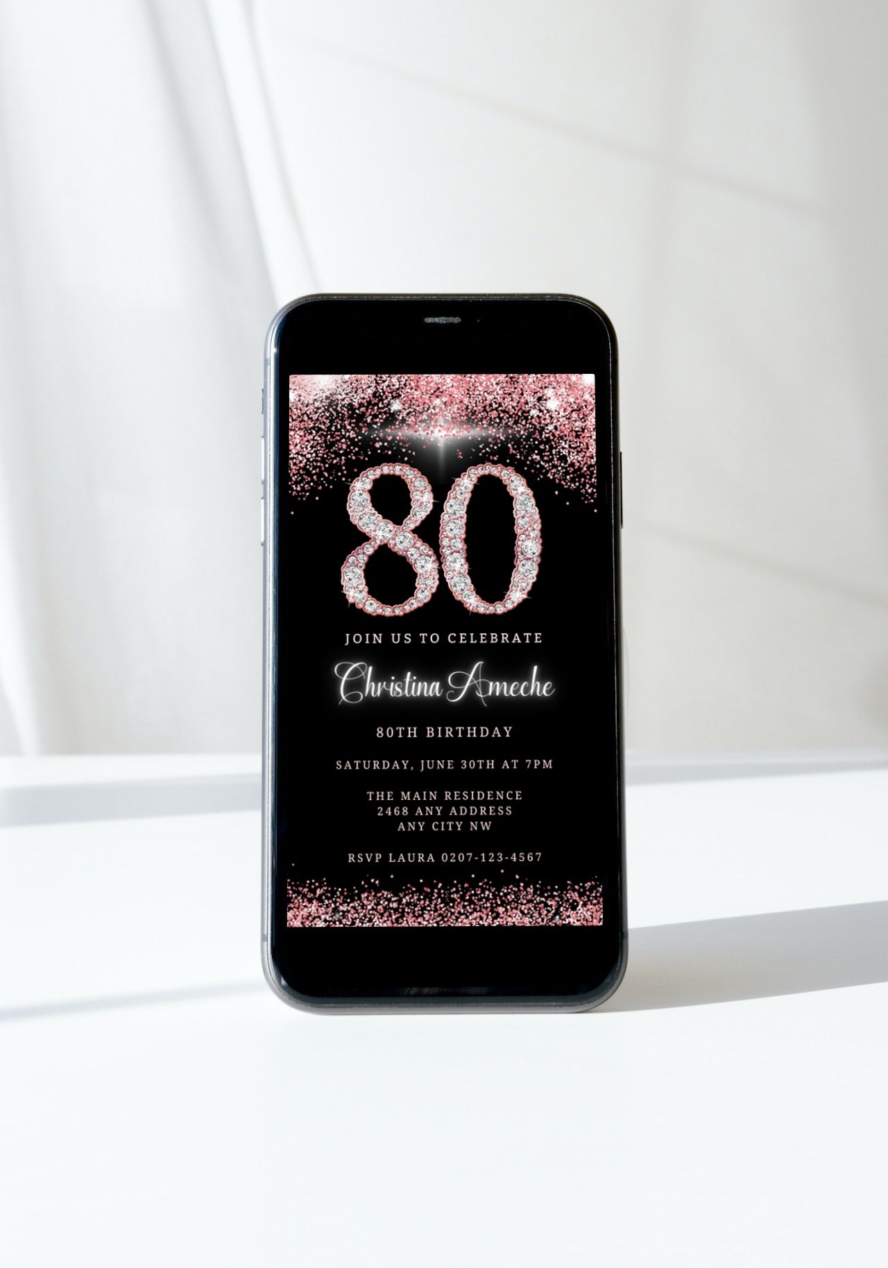 Rose Gold Diamond Glitter 80th Birthday Evite displayed on a black smartphone screen, showing customizable invitation details and pink confetti accents.