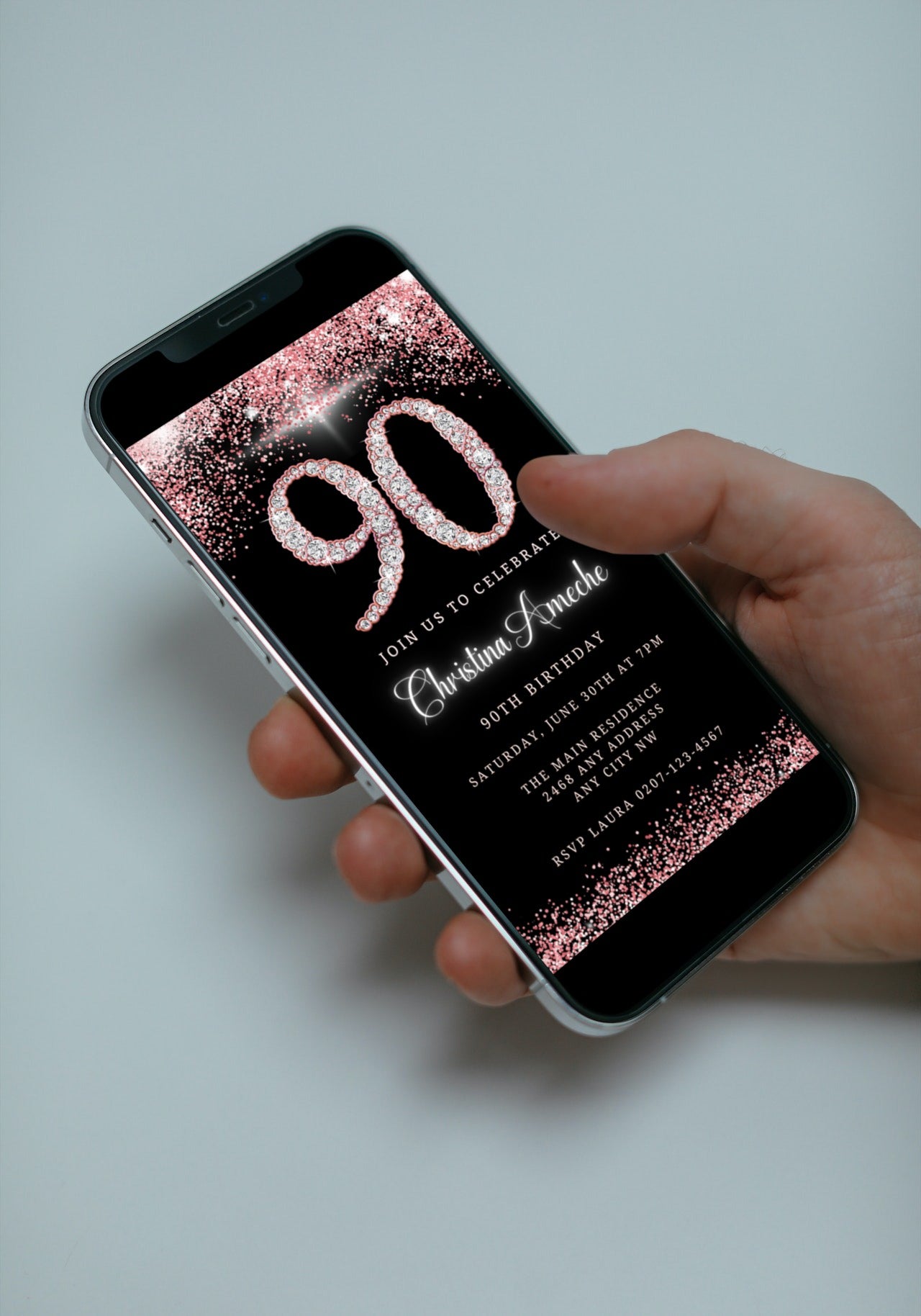 A hand holding a smartphone displaying a customizable Rose Gold Diamond Glitter 90th Birthday Evite template from URCordiallyInvited.