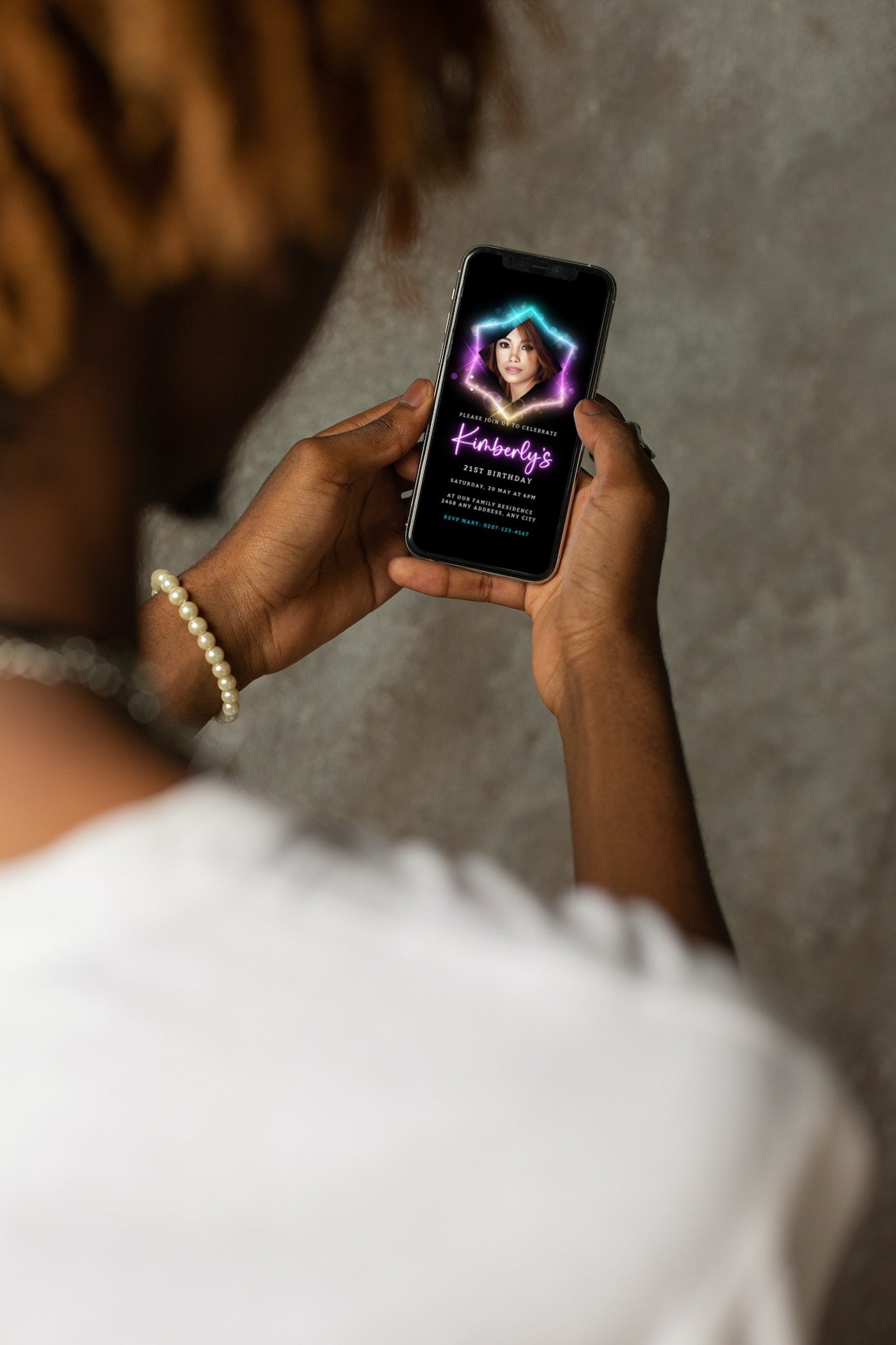 Person holding a smartphone displaying a customizable digital birthday party invitation with a woman's photo, highlighting a Colourful Neon Black Pink theme.