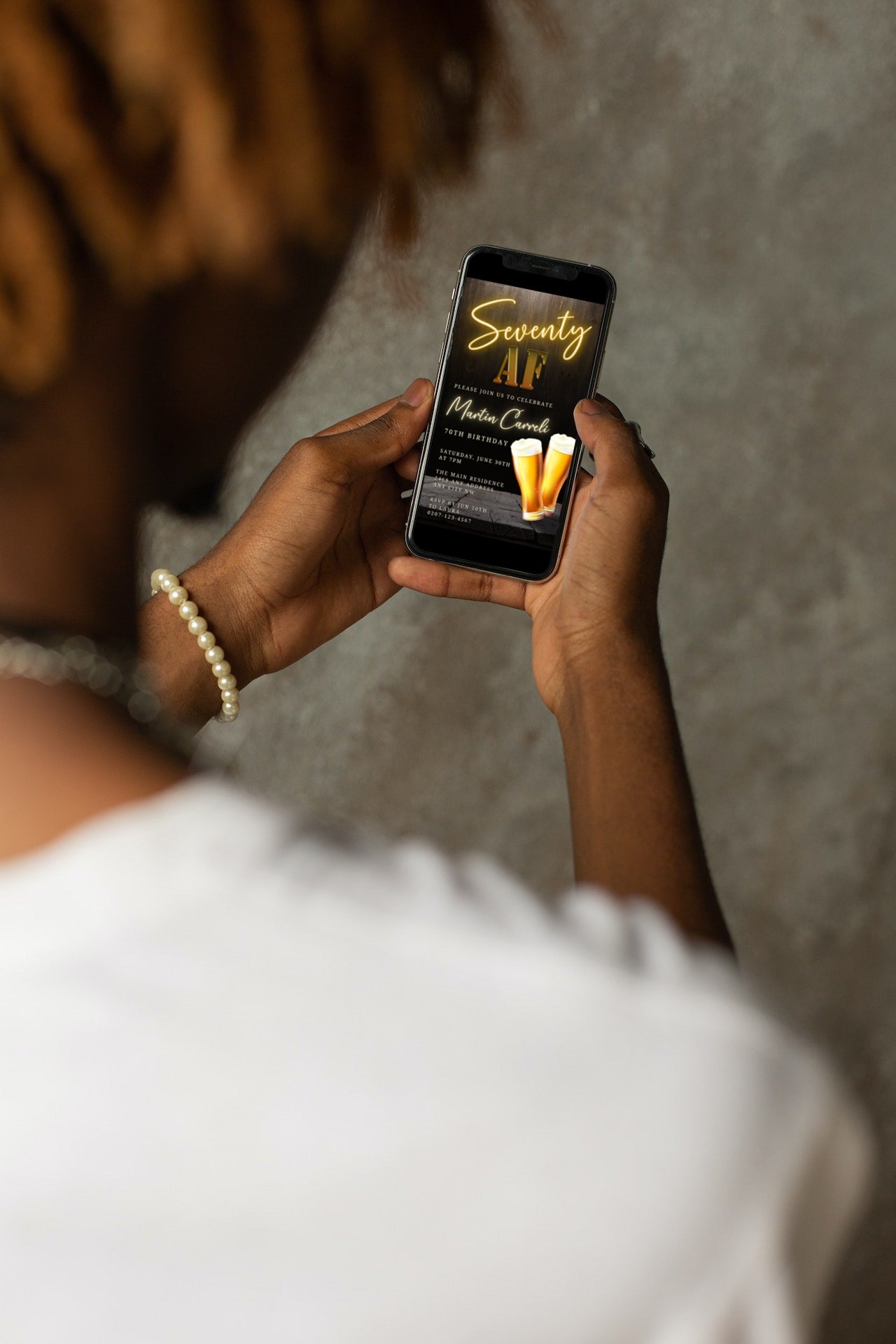 Person holding a smartphone displaying a customizable Black Gold Neon Beer | 70AF Birthday Evite from URCordiallyInvited.