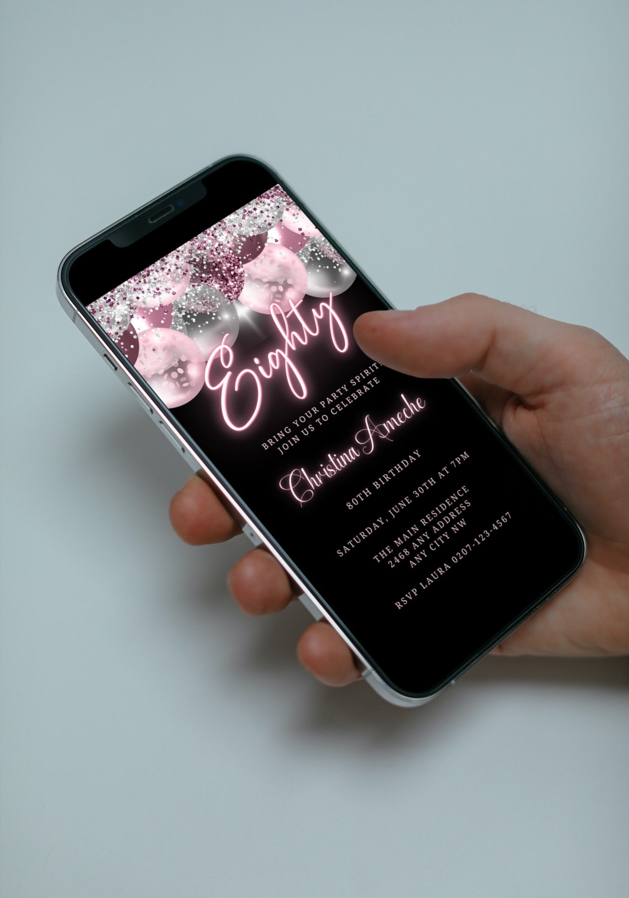 Hand holding a smartphone displaying a customizable Mauve Pink Silver Neon 80AF Birthday Evite design.