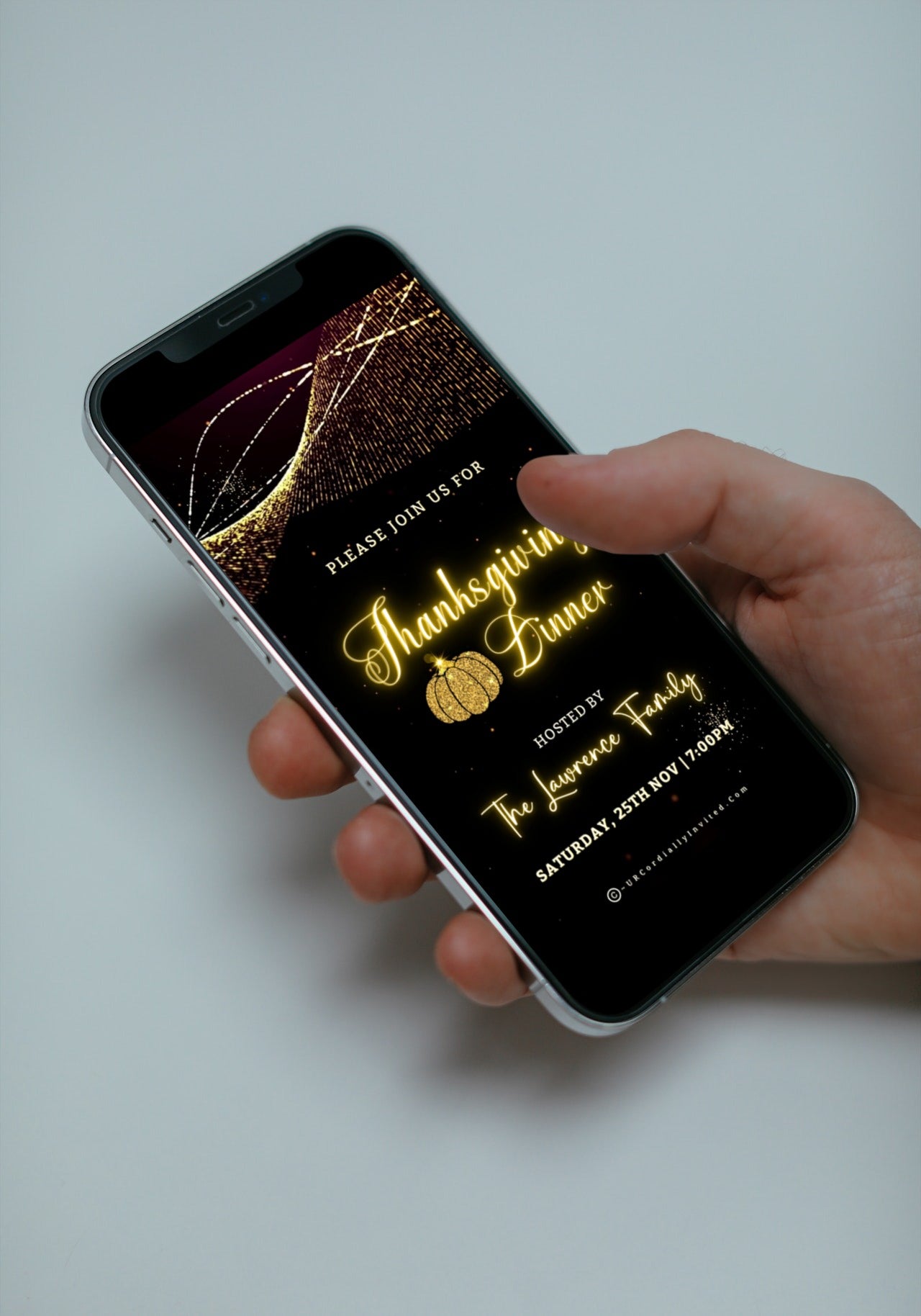 Hand holding a phone displaying the Gold Pumpkin Motion Glitter Thanksgiving Dinner Video Invite template for customization via Canva.