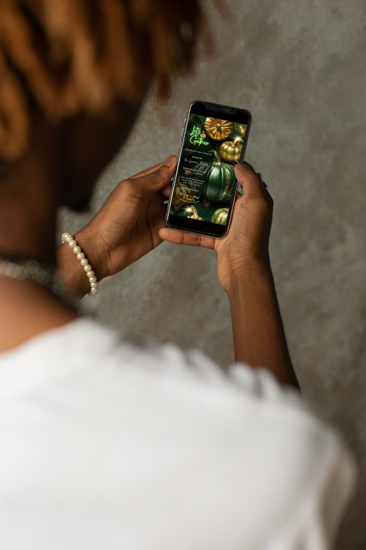 Person holding a phone displaying the Green Gold Pumpkin Glitter Thanksgiving Dinner Video Invite template, customizable in Canva.