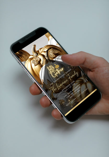 Hand holding a smartphone displaying the Gold Neon White Pumpkin Thanksgiving Dinner Video Invite, featuring elegant script over gold and white pumpkins with glittery leaves.