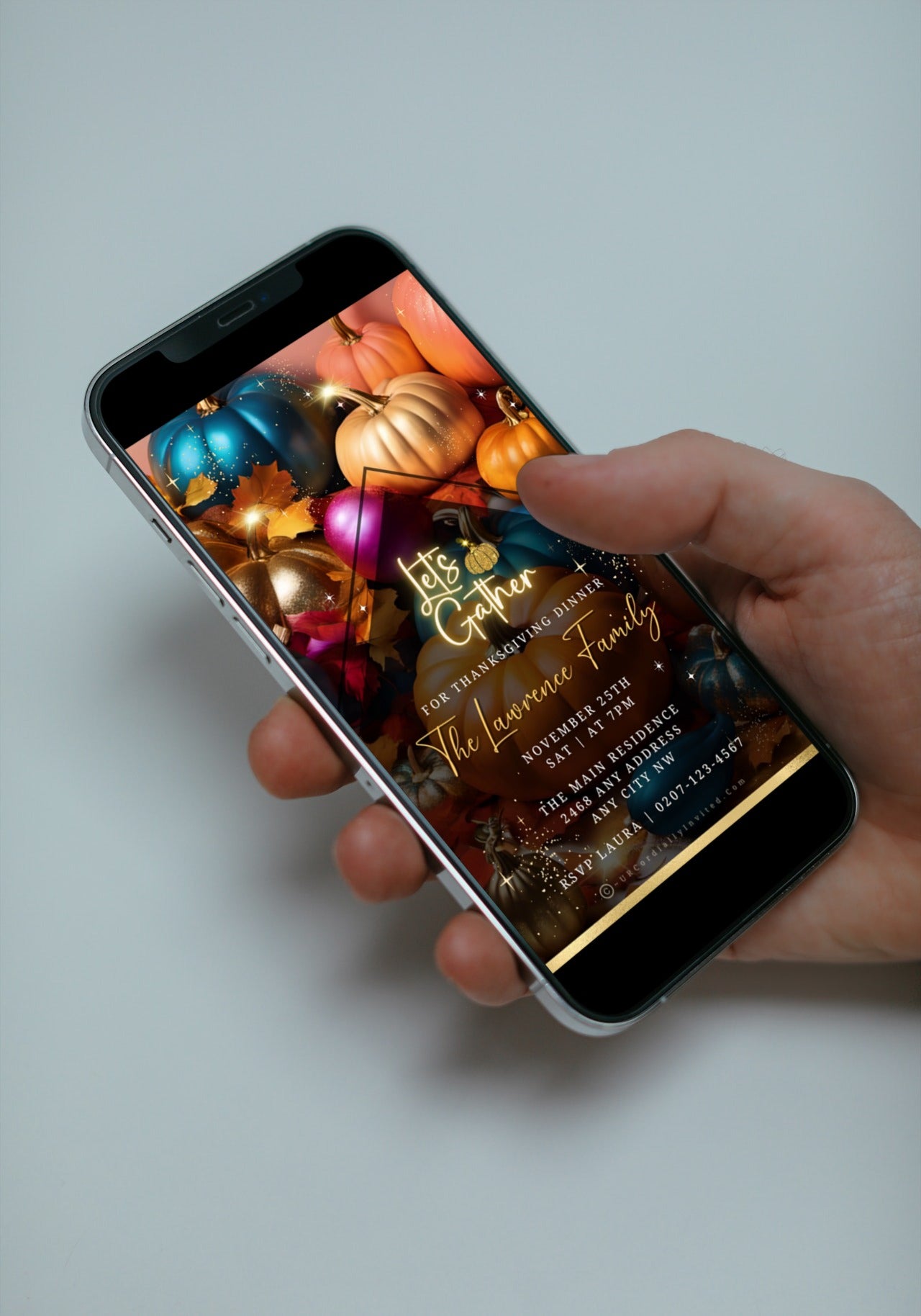 Hand holding a smartphone displaying the Multicoloured Sparkle Pumpkins | Thanksgiving Dinner Video Invite template from URCordiallyInvited.