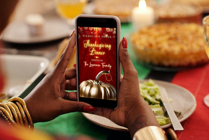 Person holding a phone displaying the Red Gold Pumpkin Glitter Thanksgiving Dinner Video Invite, customizable via Canva for digital sharing.