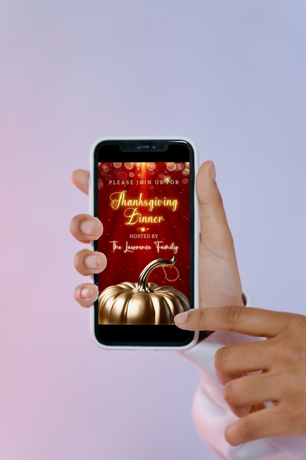 Hand holding a phone displaying the Red Gold Pumpkin Glitter | Thanksgiving Dinner Video Invite template with a gold pumpkin image.