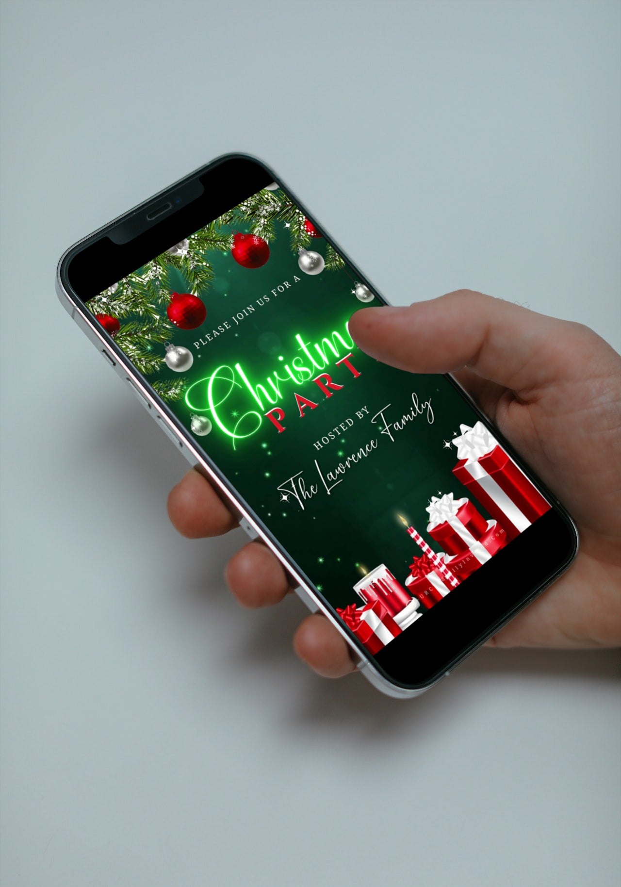 A hand holding a smartphone displaying the Neon Green Glitter Ornaments Christmas Video Invitation template from URCordiallyInvited.