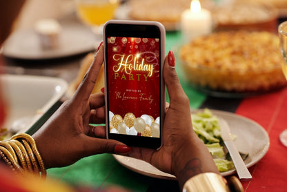 Person capturing a festive holiday party on a smartphone, showcasing the customizable Red Gold Glitter Balloons Sparkle Christmas Video Invitation from URCordiallyInvited.