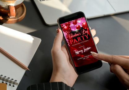 Hand holding a smartphone displaying a customizable digital invitation for a Valentine's party featuring pink and red silk neon balloons.