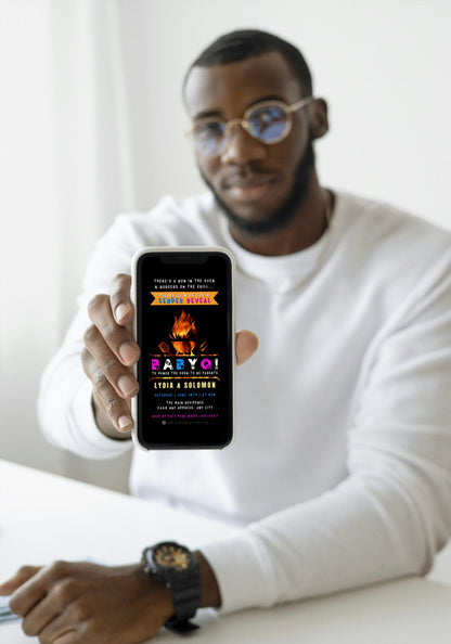 Man holding a cellphone, showcasing the customizable Animated BABYQ Flaming Grill | Digital Gender Reveal Invite on screen, designed for easy personalization via Canva app.