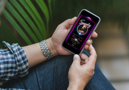 Person holding a phone displaying the 60th Birthday Video Invitation with a pink and purple oval photo frame, designed for elegant milestone celebrations.