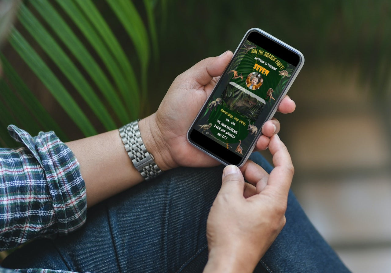 Person holding a smartphone displaying the Dinosaur Birthday Video Invitation - Jurassic Theme, showcasing customizable digital features for a personalized invitation experience.