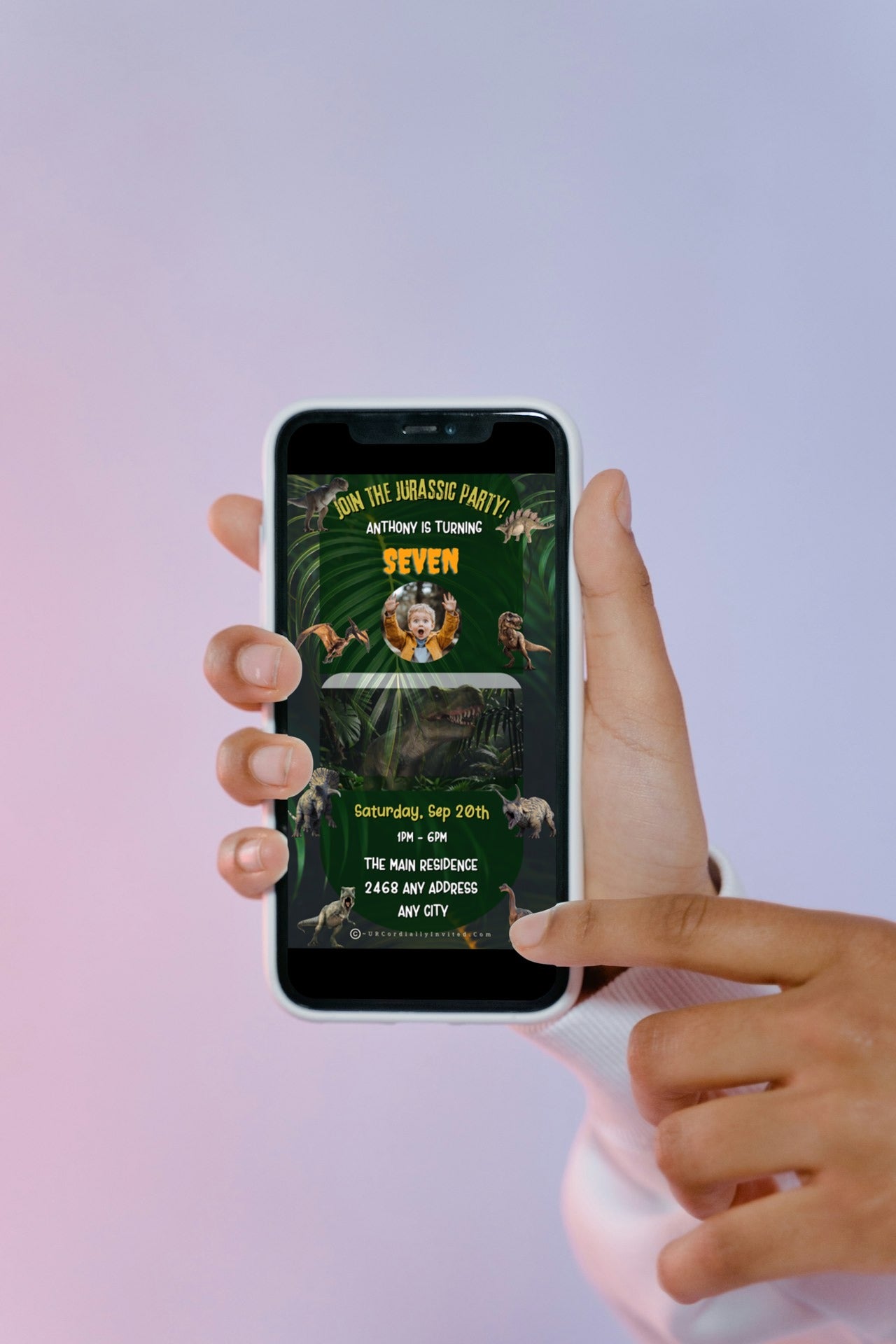 Hand holding a smartphone displaying the Dinosaur Birthday Video Invitation - Jurassic Theme, featuring vibrant tropical elements for customisable digital invitations via Canva.